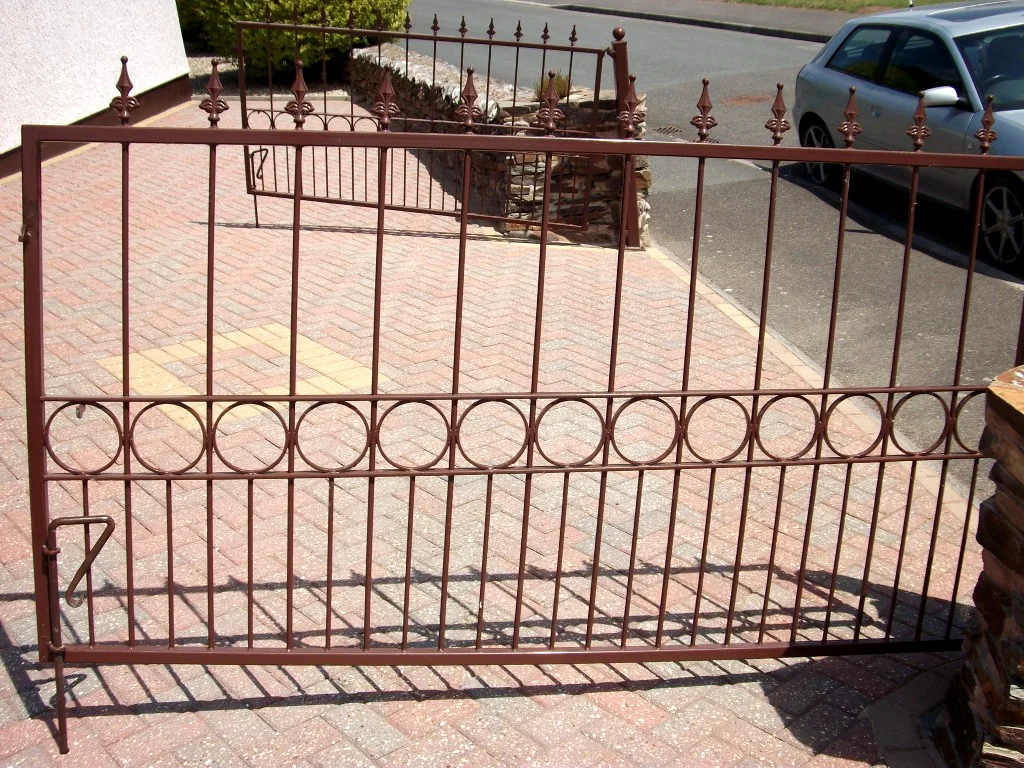 Close view of brown gate showing ring infill band and decorative spear finials