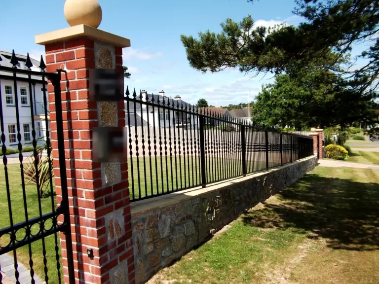 Black spear-top railings and matching gate set between red brick piers with stone caps